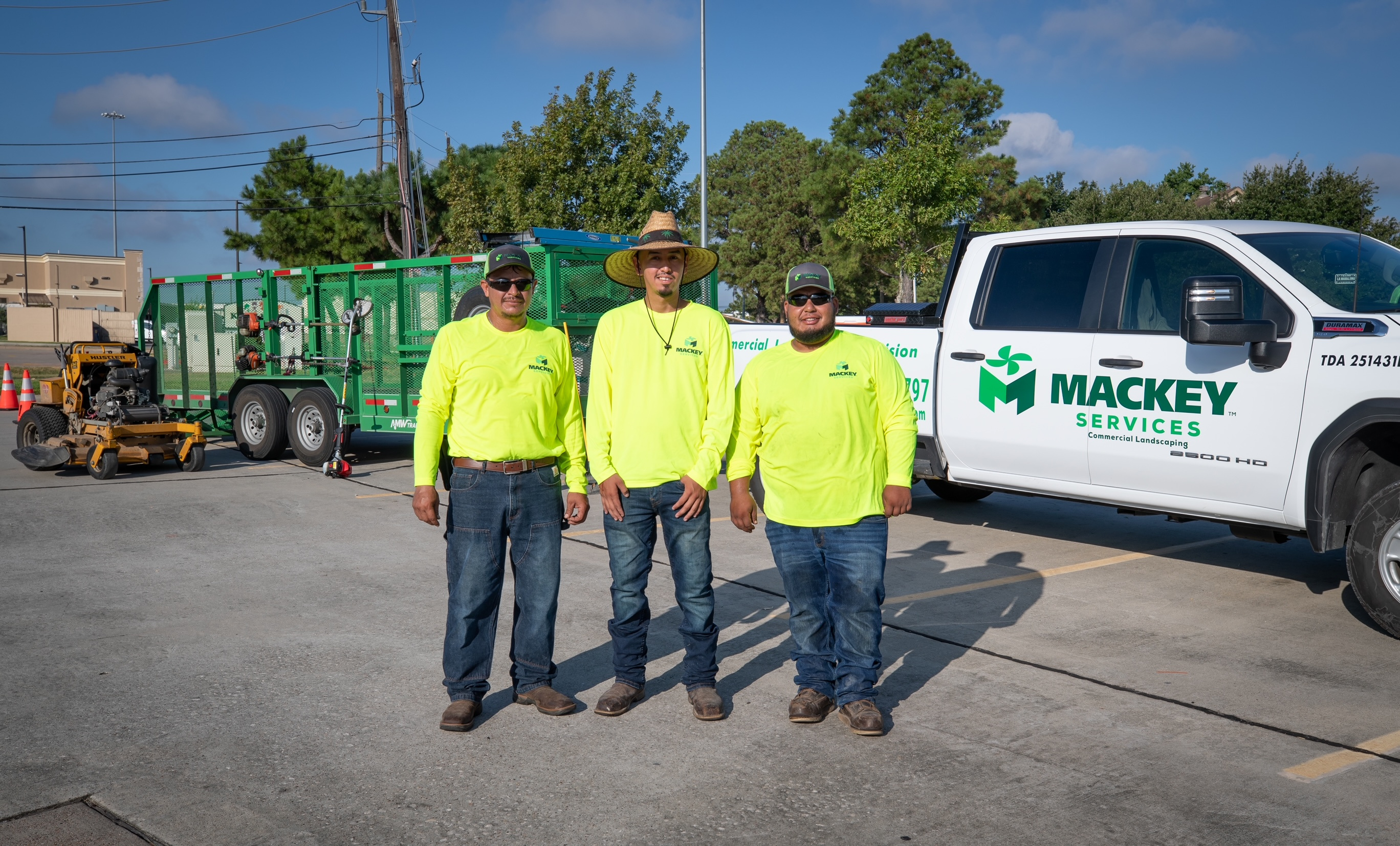 Three Mackey Services crew members with their branded truck and landscape maintenance equipment