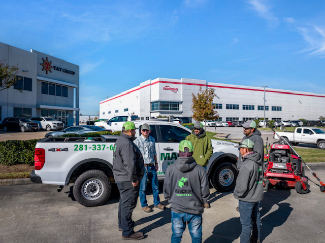 Mackey team gathered beside their service truck and landscaping equipment